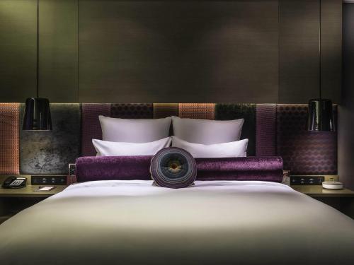 a bedroom with a large bed with purple and white pillows at Pullman Nanjing Lukou Airport in Nanjing