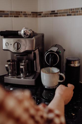 a person is holding a cup of coffee on a stove at Lithgow Falls Marysville in Marysville