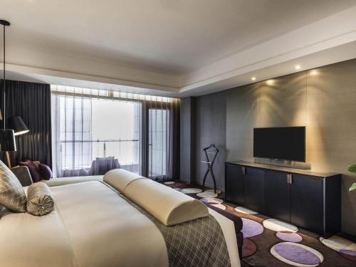 a bedroom with a large bed and a flat screen tv at Pullman Nanjing Lukou Airport in Nanjing