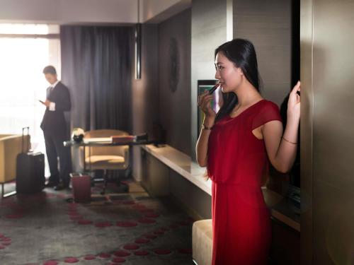 a woman in a red dress talking on a cell phone at Pullman Nanjing Lukou Airport in Nanjing