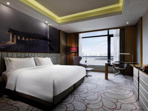 a bedroom with a large white bed and a desk at Pullman Wenzhou in Wenzhou