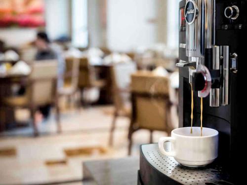 a cup of coffee is being made in a coffee machine at Pullman Changshu Leeman in Changshu