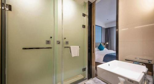 a bathroom with a shower and a sink and a bed at Echarm Hotel 1st Affiliated Hospital of Suzhou University Pingjiang in Suzhou