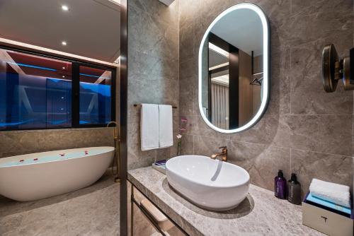 a bathroom with a tub and a sink and a mirror at Mercure Huangshan East Gate in Huangshan