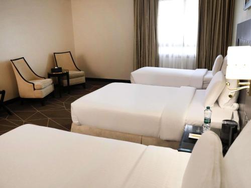 a hotel room with two beds and two chairs at Pullman Zamzam Madina in Al Madinah