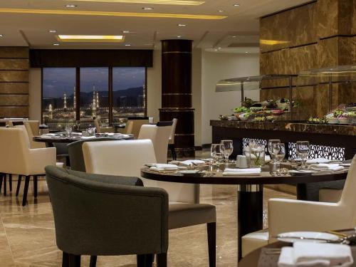 a restaurant with tables and chairs with a view at Pullman Zamzam Madina in Al Madinah