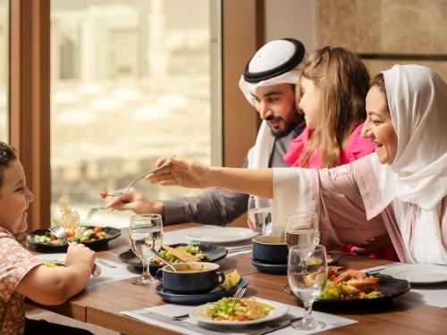 a group of people sitting around a table eating food at Pullman Zamzam Madina in Al Madinah