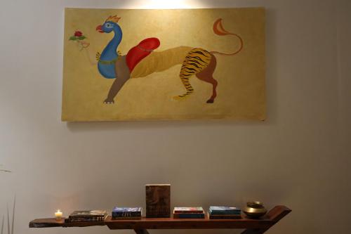 a painting of a lion and a peacock on a wall at Hans BnB Charming stay amidst nature in Bīr