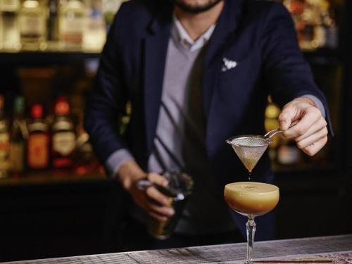 a bartender making a cocktail at a bar at Pullman Melbourne On the Park in Melbourne