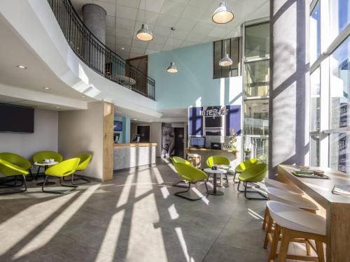 a lobby with yellow chairs and tables in a building at ibis budget Nice Californie Lenval in Nice