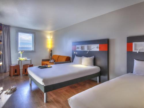 a hotel room with two beds and a desk at ibis budget Nice Californie Lenval in Nice