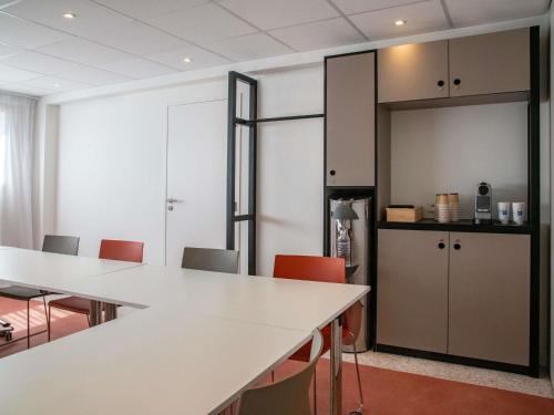 a room with tables and chairs and a kitchen at ibis budget Nice Californie Lenval in Nice