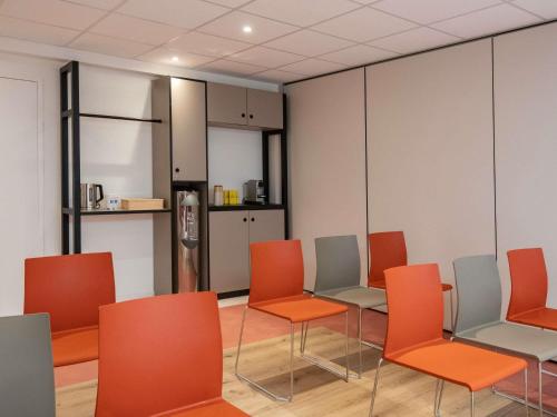 a waiting room with orange chairs and a refrigerator at ibis budget Nice Californie Lenval in Nice