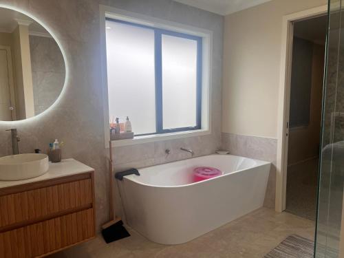 a white bath tub in a bathroom with a window at 23 Texel Crescent Black brick house in West Melton