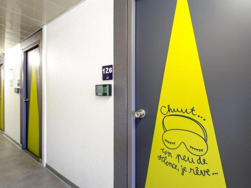 a sign on the door of a hallway with a hat on it at Ibis Budget Fréjus Capitou in Fréjus