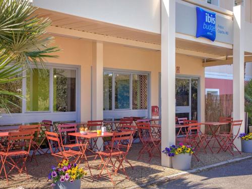 a restaurant with tables and chairs in front of a building at Ibis Budget Fréjus Capitou in Fréjus