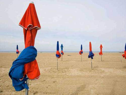 a row of closed umbrellas on the beach at Hotel Ibis Budget Deauville in Deauville