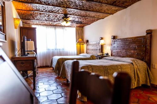 a hotel room with two beds and a television at Quinta Don Jose Boutique Hotel in Guadalajara