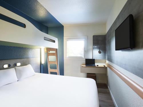 a bedroom with a bed and a desk with a laptop at Ibis budget Rouen Petit Quevilly in Le Petit-Quevilly