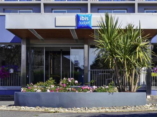 a building with a lot of flowers in front of it at ibis budget Pau Lescar in Lescar