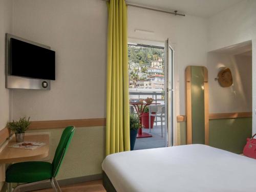a bedroom with a bed and a table and a window at ibis budget Menton Bord de Mer in Menton