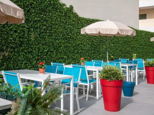 an outdoor patio with tables and chairs and an umbrella at ibis budget Menton Bord de Mer in Menton