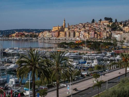 a city with a marina and buildings and palm trees at ibis budget Menton Bord de Mer in Menton