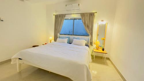 a white bed in a room with a window at ABN Stays in Anjuna