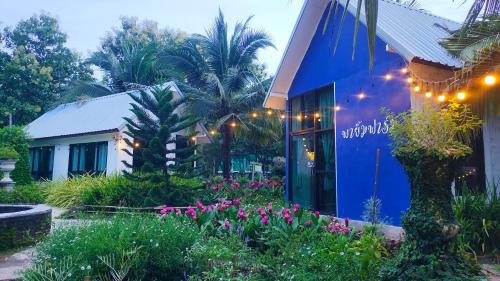 ein blaues Gebäude mit Blumen davor in der Unterkunft Payim farm พายิ้มฟาร์ม in Ban Nam Khrai