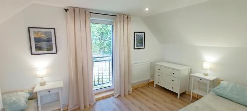 a bedroom with a bed and a large window at Pine Peak Holiday House Sosnówka in Sosnówka
