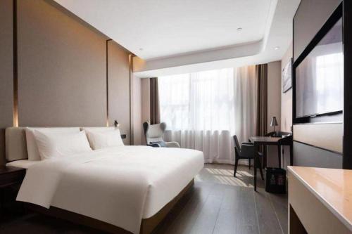a hotel room with a large white bed and a desk at Atour Hotel Taiyuan Inner Ring in Taiyuan