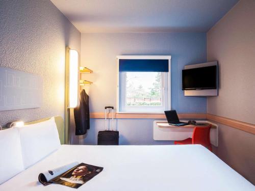 a hotel room with a bed and a window at ibis budget London Barking in Barking