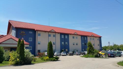 a large building with cars parked in a parking lot at Iris Hotel in Oradea