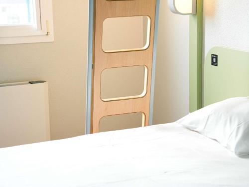 a room with a bed and a closed door at ibis budget Caen Porte de Bretagne in Bretteville-sur-Odon