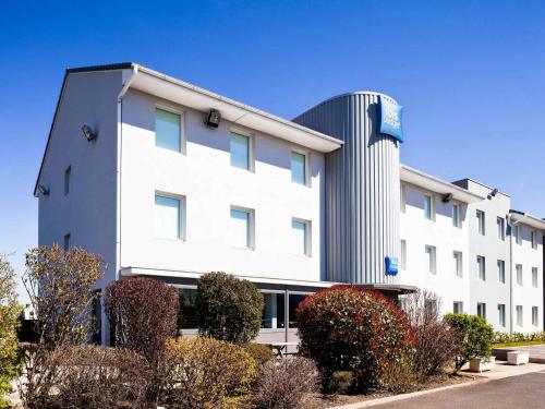 a large white building with bushes in front of it at ibis budget Clermont Ferrand Nord Riom in Riom