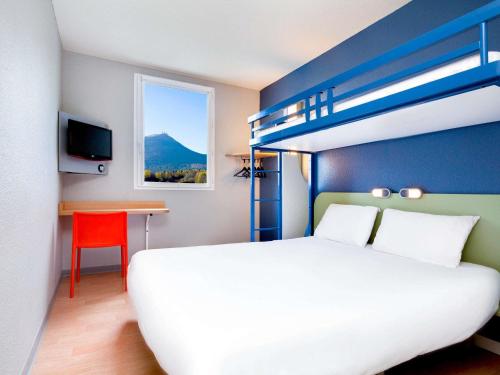 a bedroom with a white bed and a blue wall at ibis budget Clermont Ferrand Nord Riom in Riom