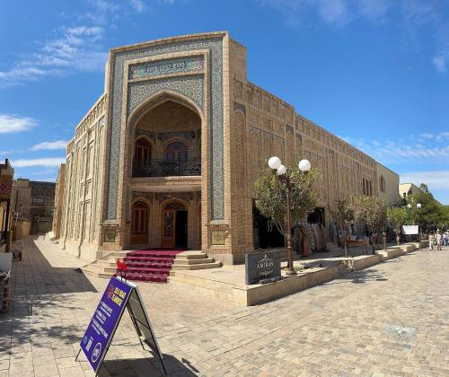 Un gran edificio de ladrillo con un cartel delante. en AMIRAN Boutique, en Bukhara