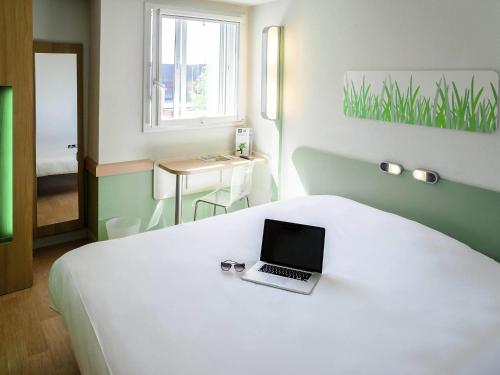 a bedroom with a bed with a laptop on it at ibis budget Aeroport le Bourget Garonor in Le Blanc-Mesnil