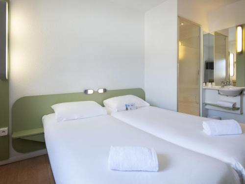 a bedroom with a large white bed and a bathroom at ibis budget Ajaccio in Ajaccio