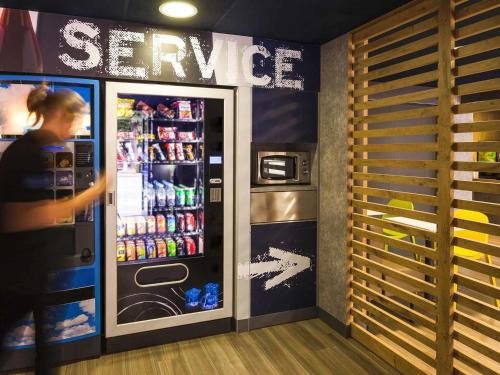a woman is standing in front of a soda machine at Ibis Budget Madrid Calle 30 in Madrid