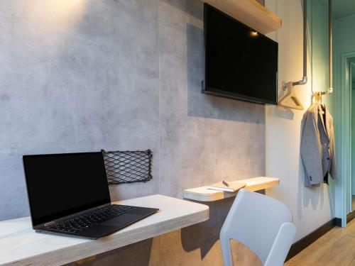 a laptop computer sitting on a desk with a chair at ibis budget Saint Dié des Vosges in Saint Die