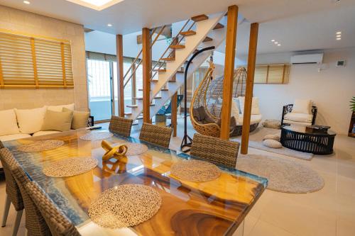 a living room with a glass table and a staircase at ReVIERA Resort Villa in Chatan