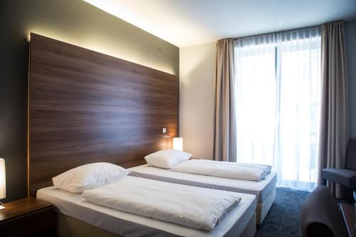 two beds in a hotel room with a large window at Hotel Sliško in Zagreb