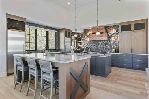 a kitchen with blue cabinets and a large island with bar stools at 11981 N Gemini Way SkyRidge 5BR Home with Hot Tub home in Keetley