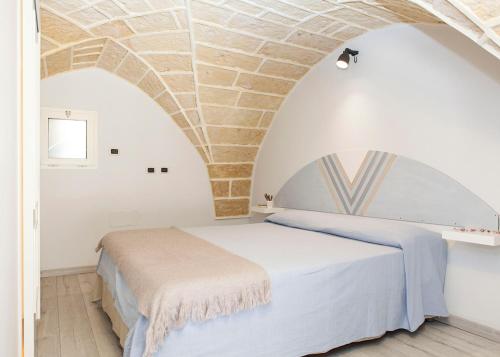 a bedroom with a white bed with a stone ceiling at Alle Volte Salento in Trepuzzi