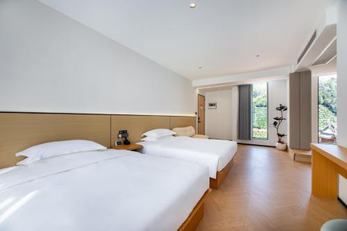 a bedroom with two beds and a window at Flower Hotel Jingxian Yishu Tea House in Xuancheng