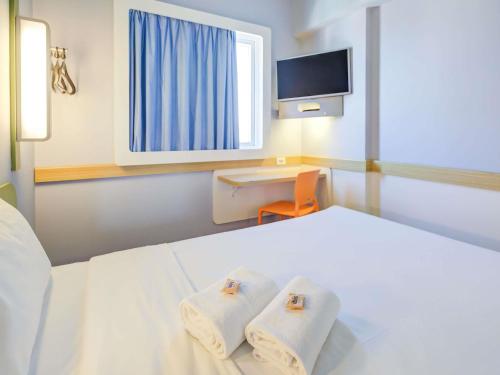 a bedroom with a white bed with towels on it at ibis budget Rio de Janeiro Nova America in Rio de Janeiro