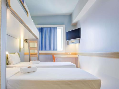 a hotel room with two beds and a tv at ibis budget Rio de Janeiro Nova America in Rio de Janeiro