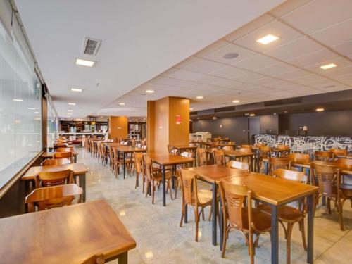 an empty restaurant with wooden tables and chairs at ibis budget Rio de Janeiro Nova America in Rio de Janeiro