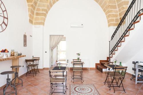 een kamer met tafels en stoelen en een trap bij Alle Volte Salento in Trepuzzi